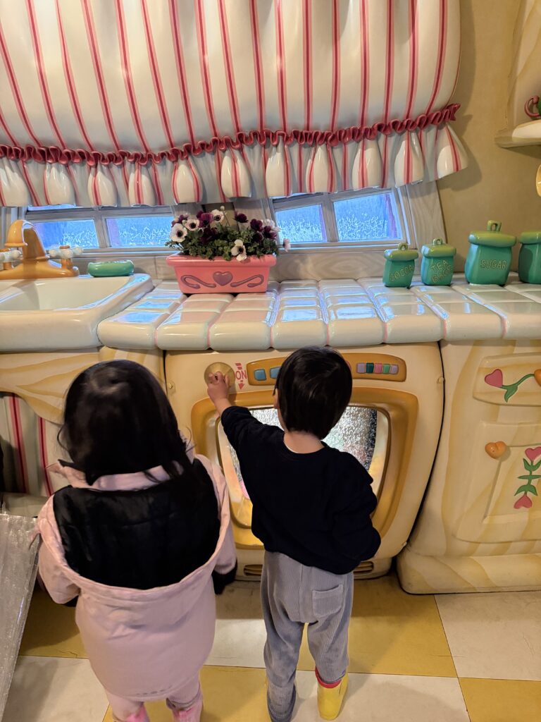 ディズニーランドのミニーの家で遊んでいる男女双子の写真